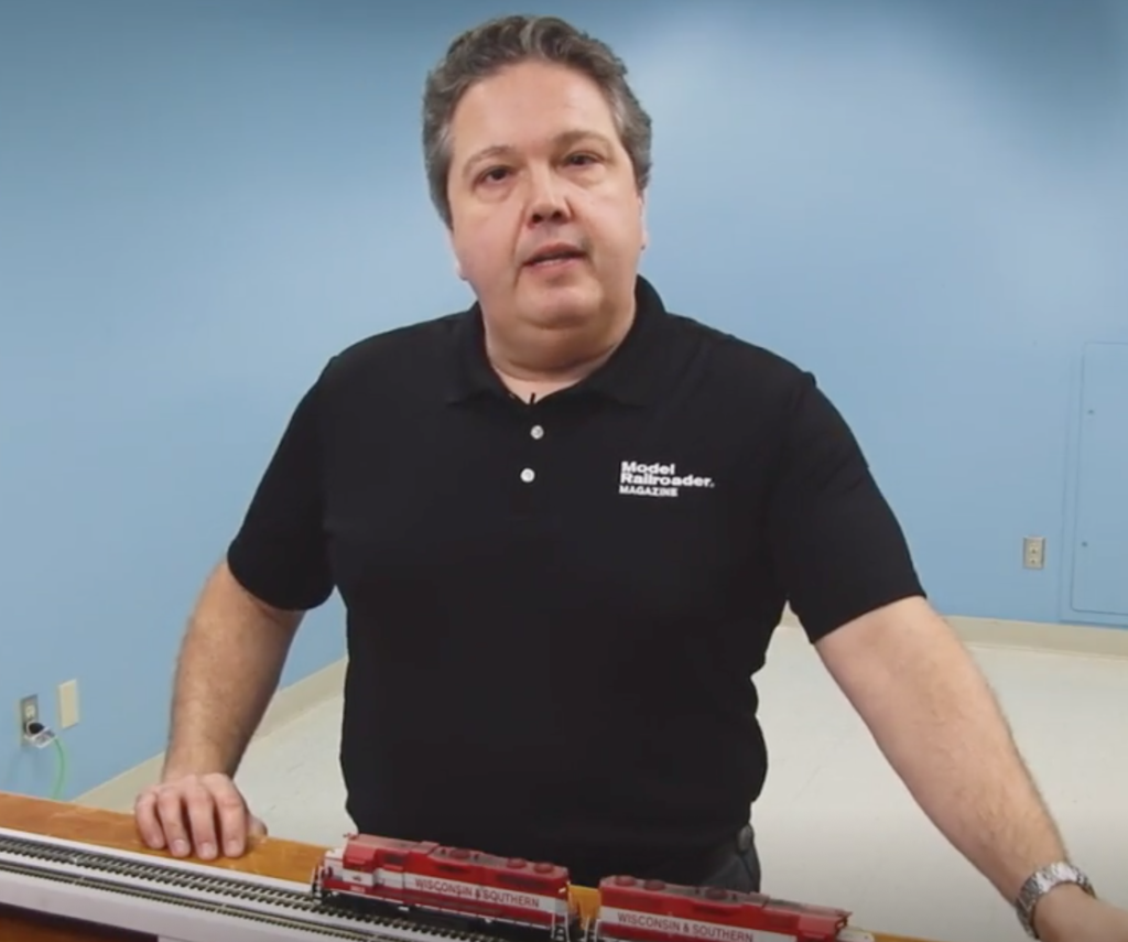 Man standing at a table with model diesel locomotives.