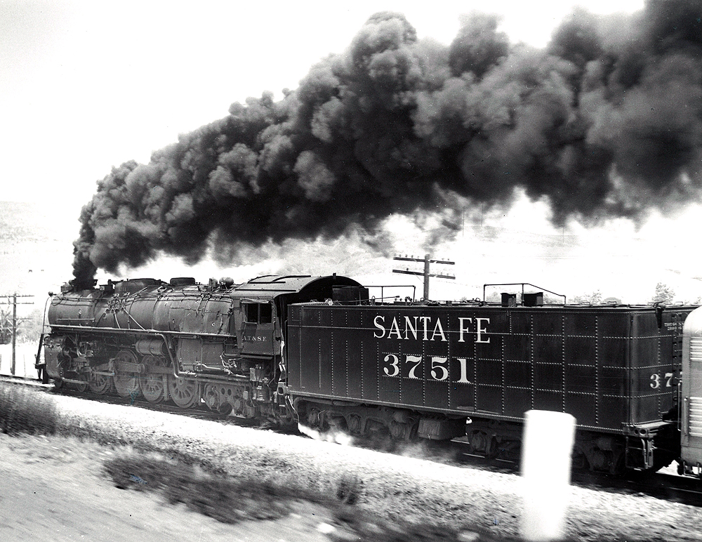 A train speeding by with black smoke coming out of its chimney