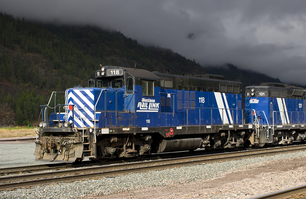 A blue and white train passing by on a stormy day