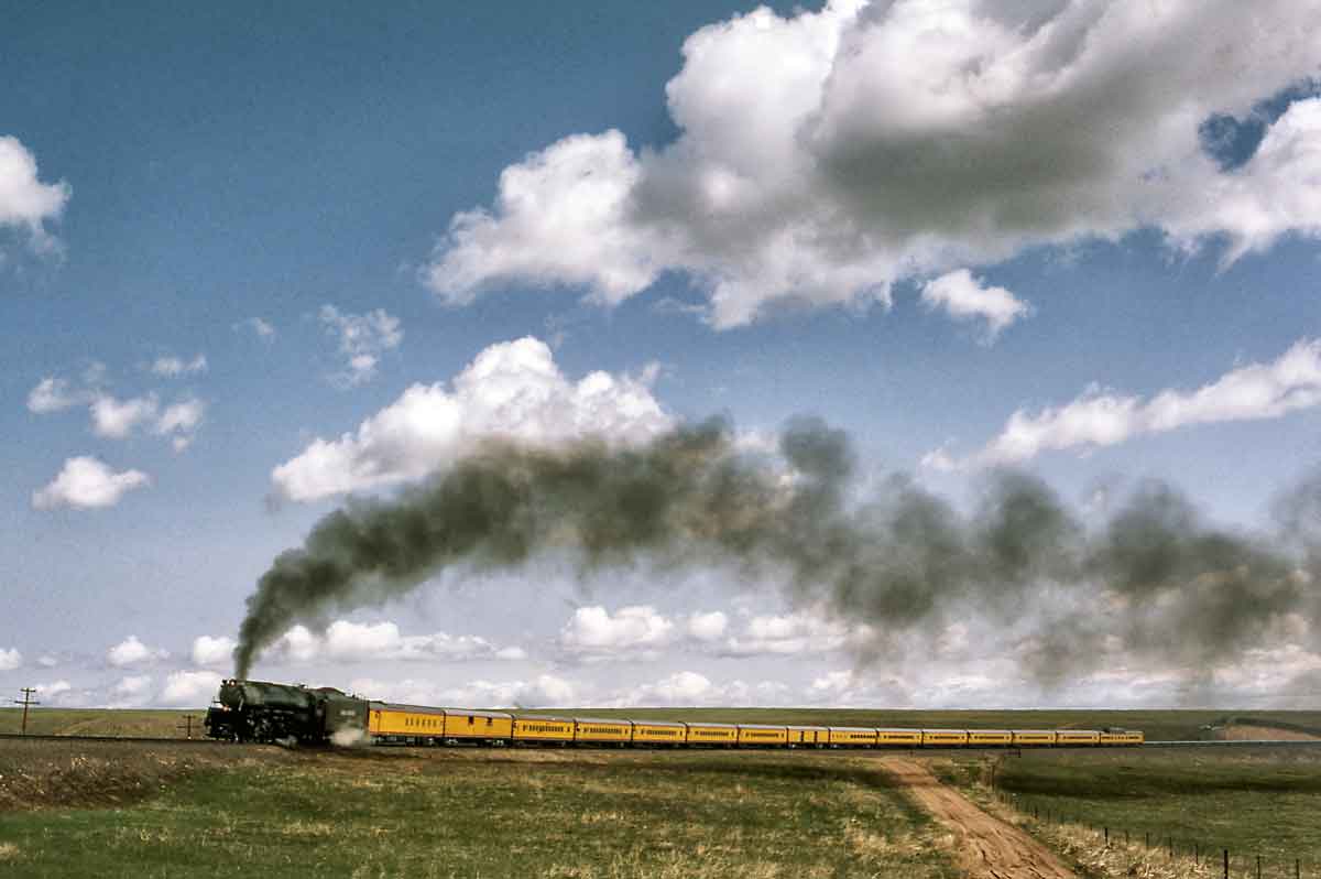 Smoking steam locomotive with yellow passenger train