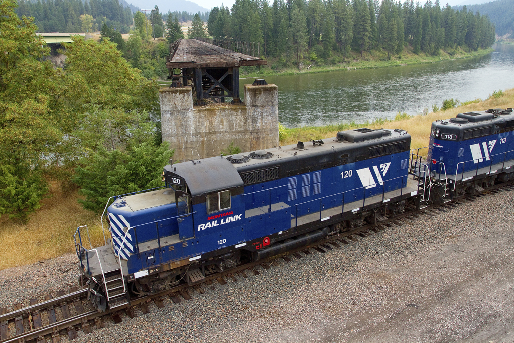 An overhead shot of a blue and white train passing by some water