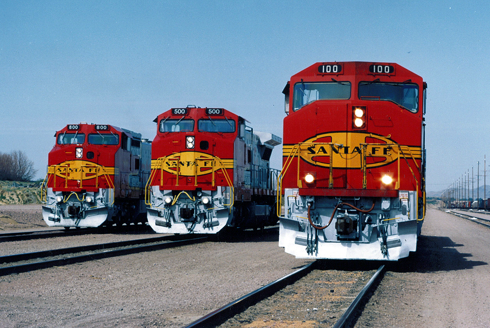 Three red and yellow santa fe trains sitting on the tracks