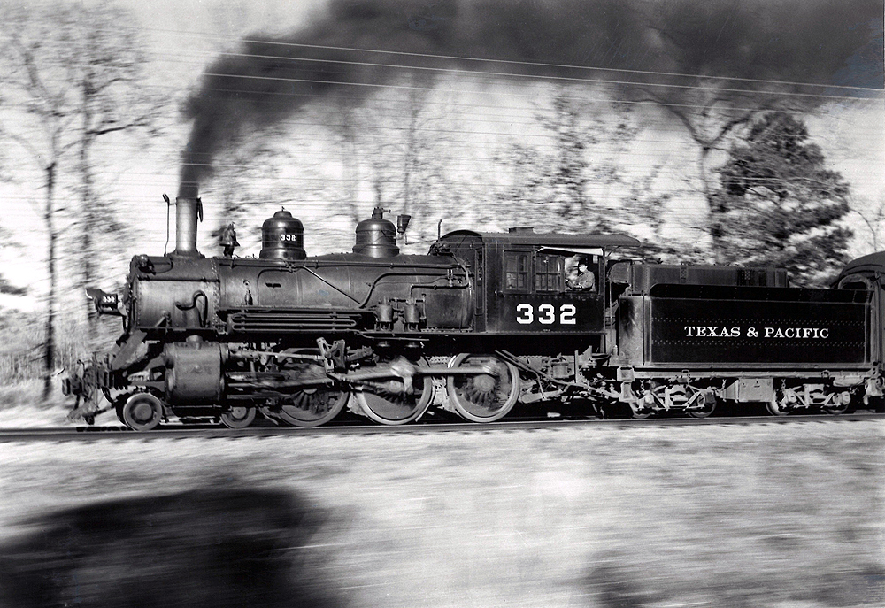 A locomotive fastly moving by with black smoke coming out of its chimney