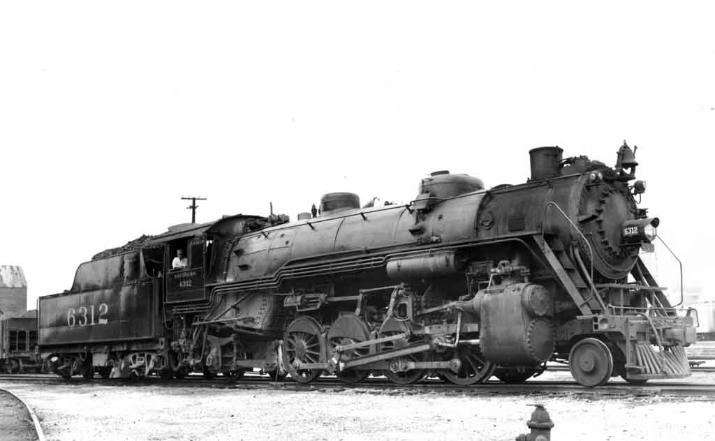 Stationary steam locomotive with man leaning out of the cab window