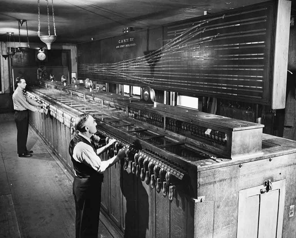 Men standing at control panel for train yard trackage