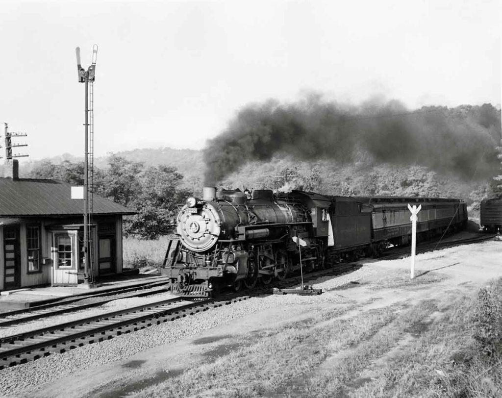 Smoking steam locomotive with passenger train by wooden station