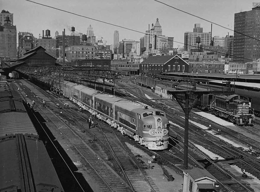 Streamlined passenger train departing station under signal bridge