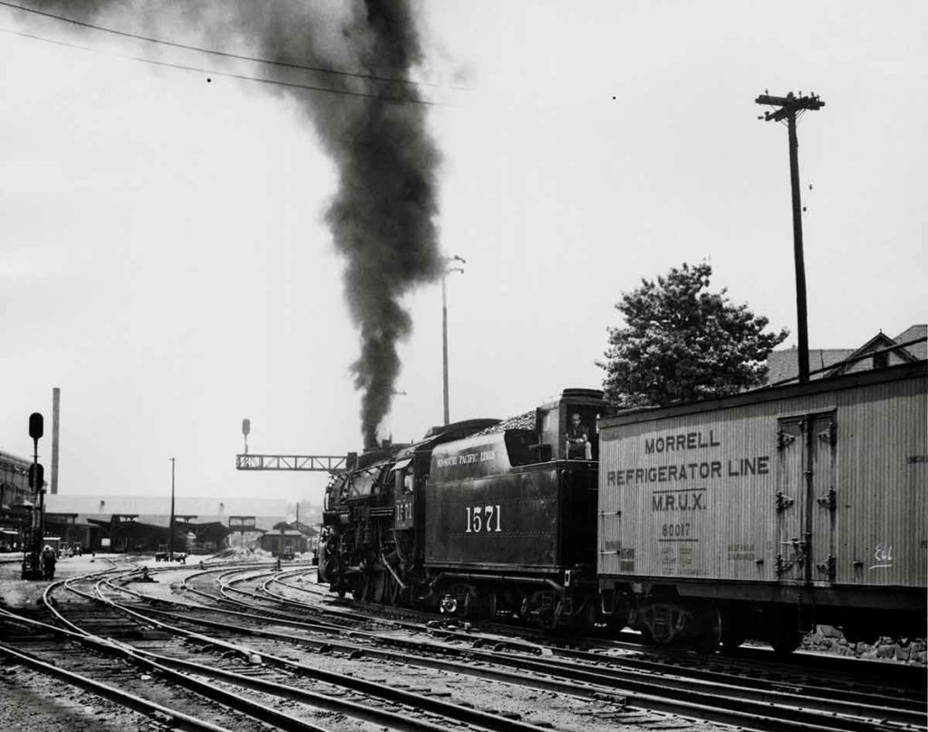 Smoking steam Missouri Pacific locomotives with man on tender