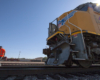 The front of the union pacific train parked on the tracks as a worker walks by