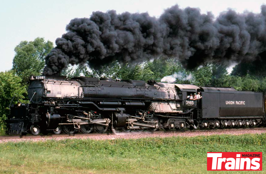 Smoking steam locomotive with multiple people standing in cab