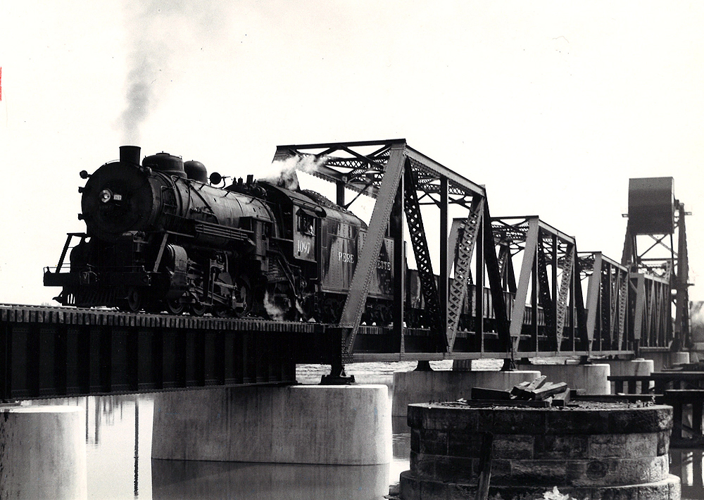 A black and white photo of Mikado 1097 moving over a bridge