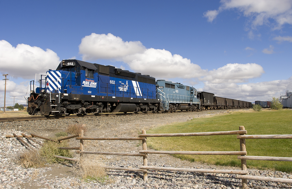 A blue train passing by a rural area