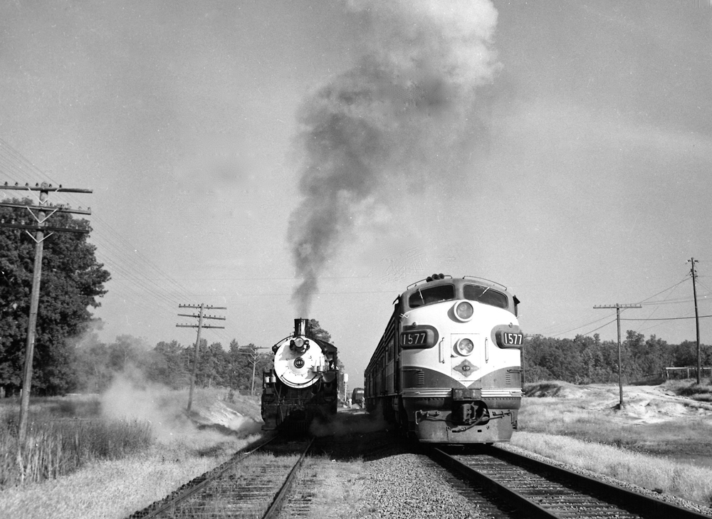 A black and white photo of two locomotives side by side on the tracks 