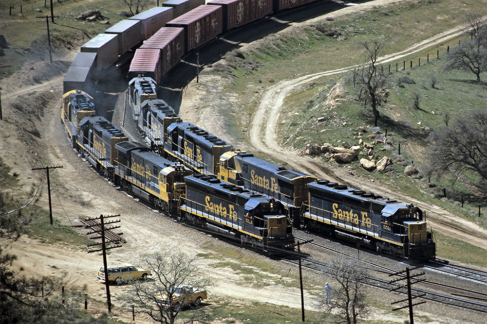 Two navy blue and yellow Santa Fe locomotives turning the bend at the same time