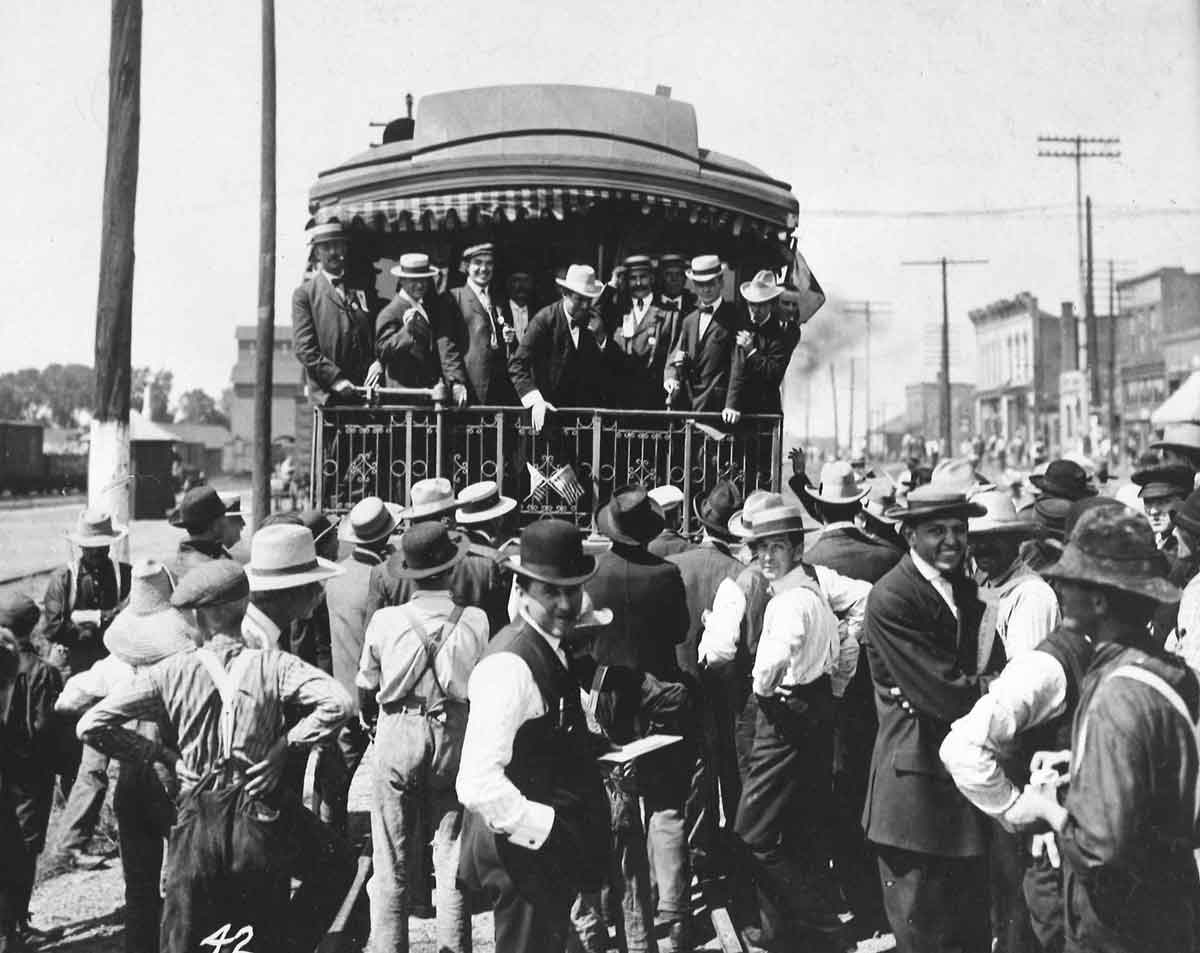 People crowd around rear of passenger train