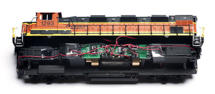 TheprintedcircuitboardismountedontopofthemotorandflywheelsSoundTraxxmakesaDigitalCommandControlDCCsounddecoderthatreplacesthisboard