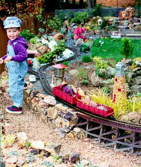 smiling child next to garden railway