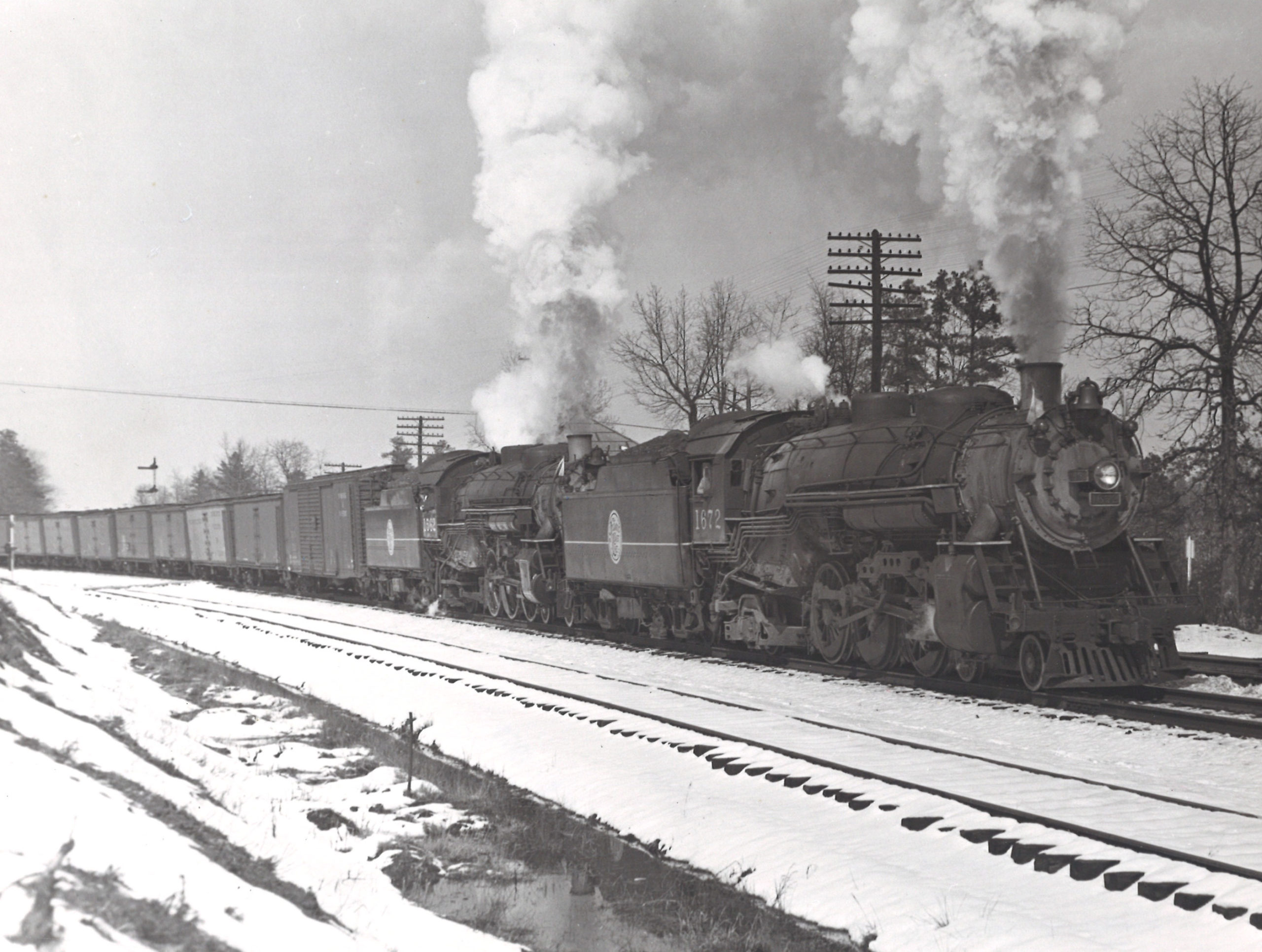 A black and white photo of a steam locomotive on a snowy day