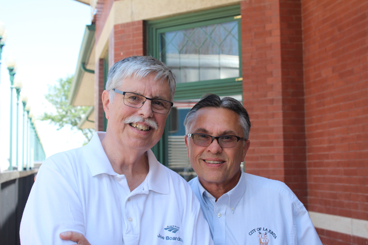 Two men pose outside train station