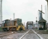 Green diesel switcher on diamond crossing by tower and bridges