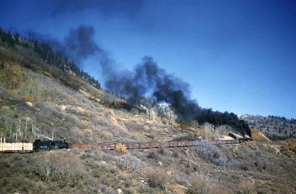 A distant shot of a train traveling through the mountains