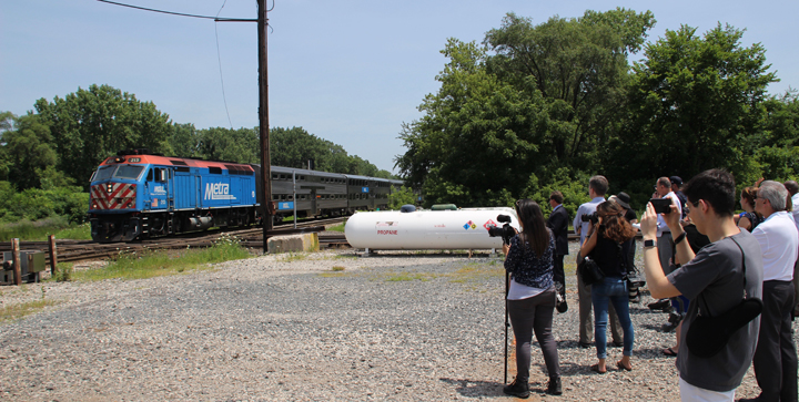 Metra train passes media members taking photos and video