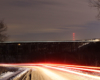 A distant shot of a lit train passing over a bridge in the dark