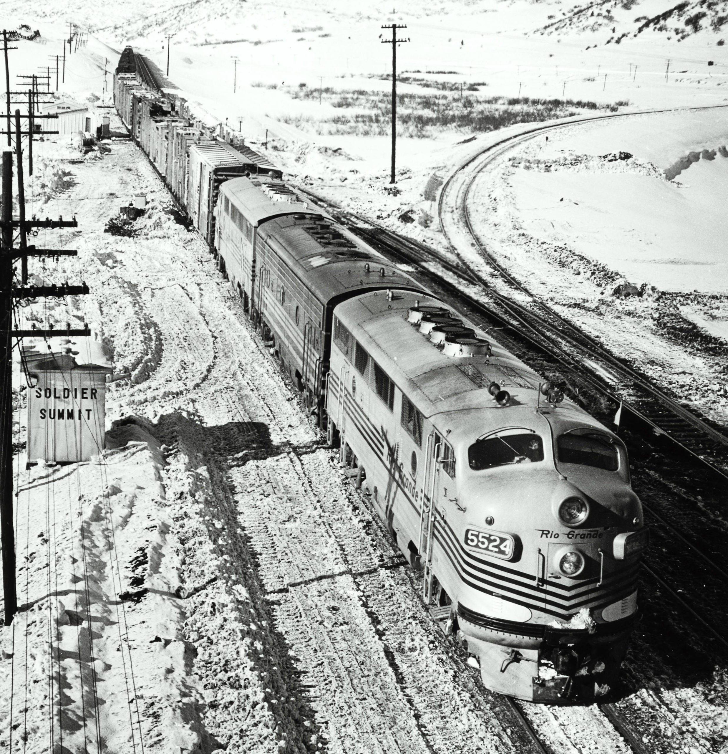 A black and white diesel locomotive on the tracks on a snowy day