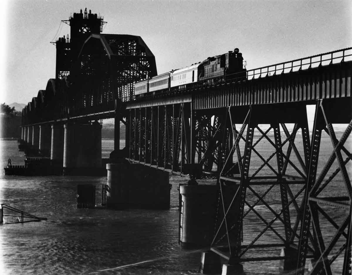 Diesel locomotive with three passenger cars on large bridge