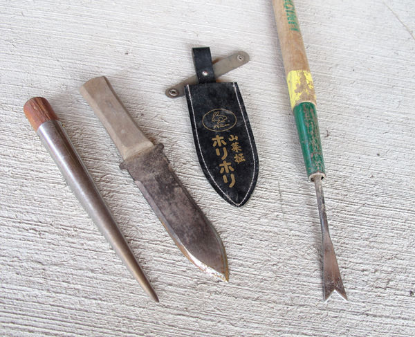 four weeding tools on concrete