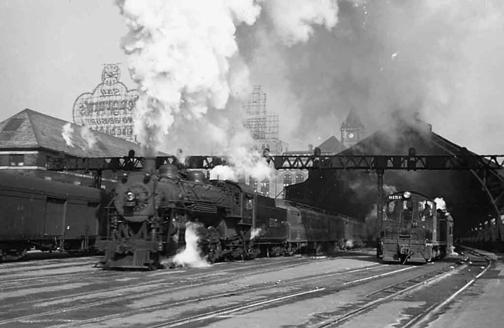 a steam passenger train leaving a station