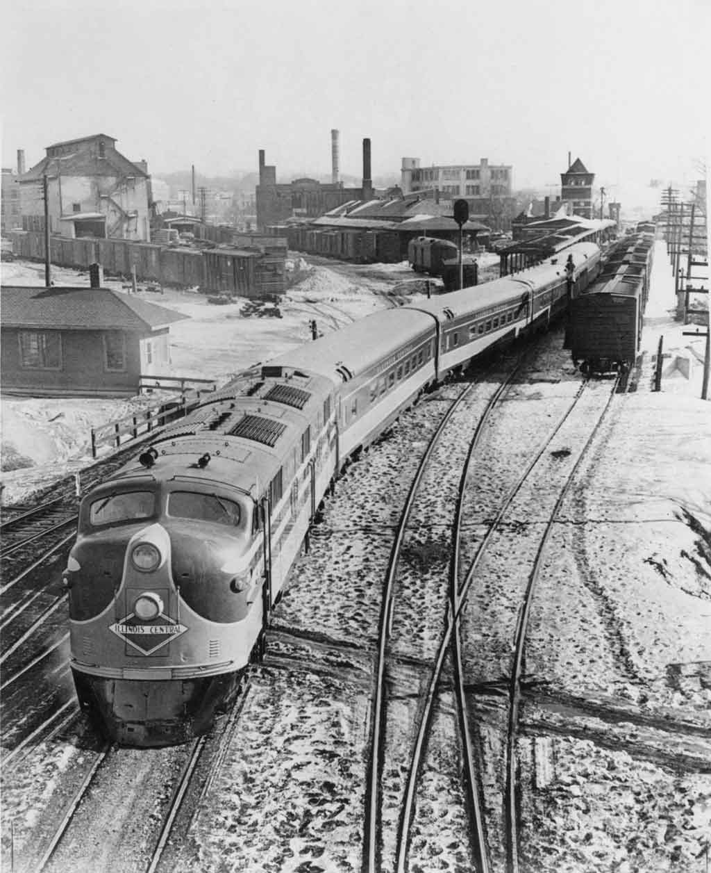 a diesel passenger train with buildings in the background