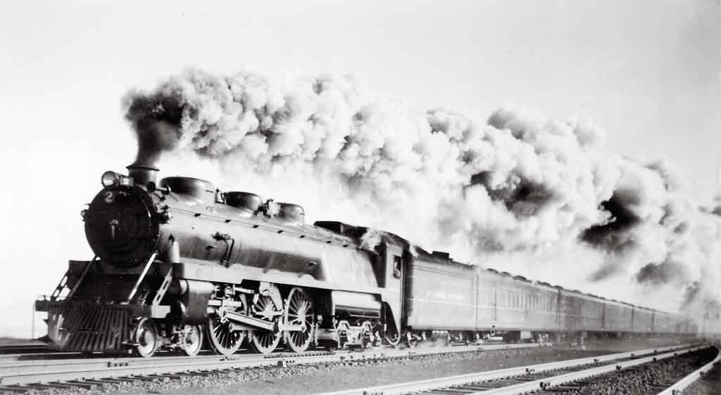 A black and white photo of a train with a lot of white smoke coming out of it