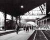 A black and white photo of people walking through a train station