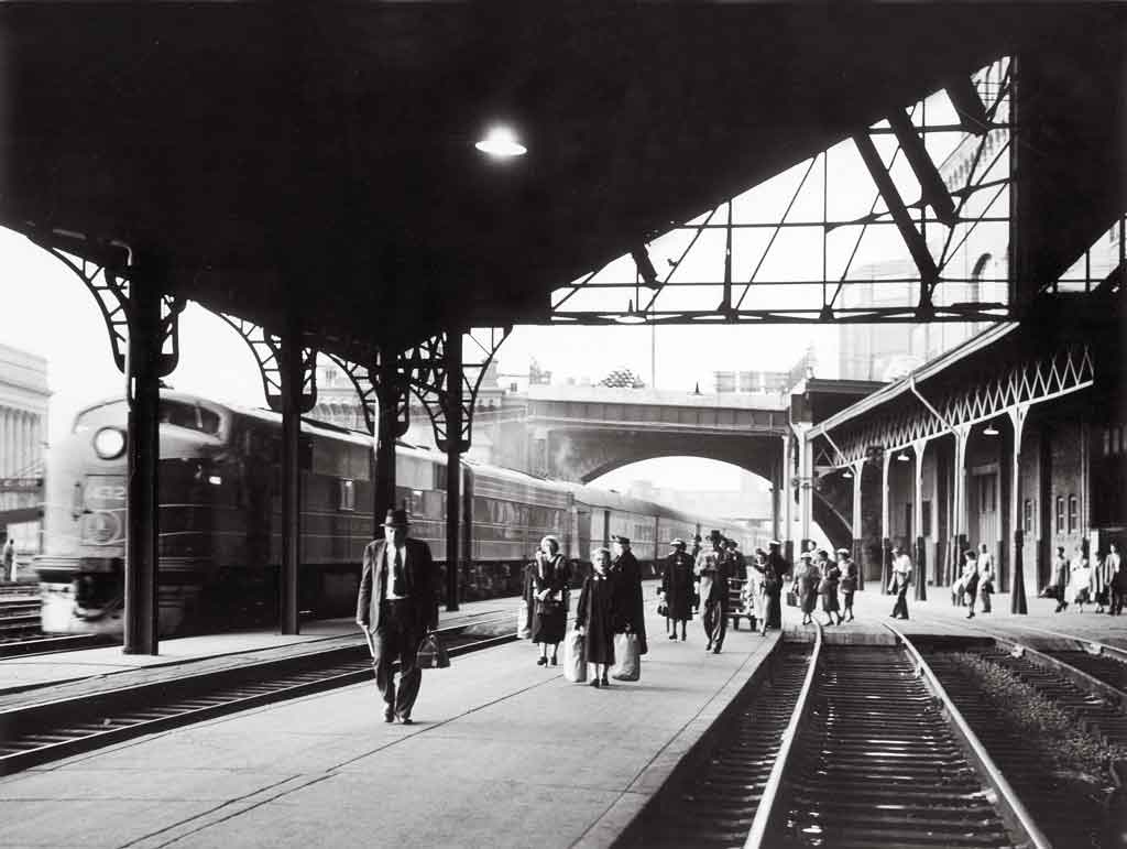A black and white photo of people walking through a train station