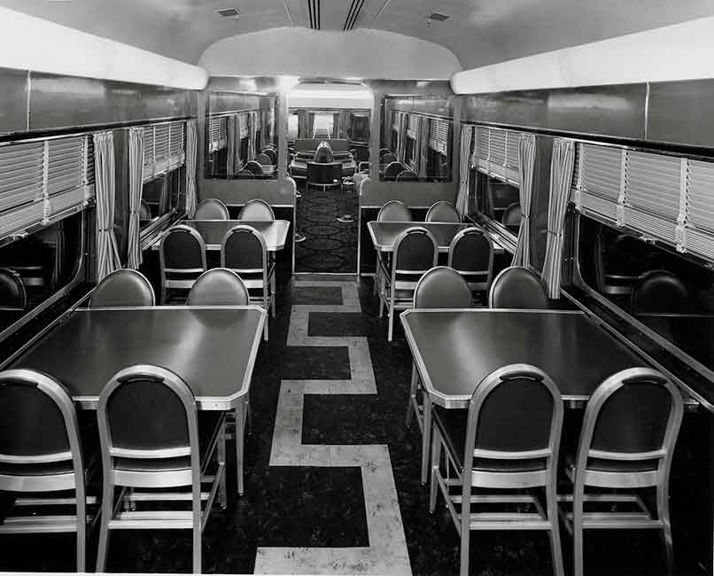 A black and white photo of the inside of an empty lounge diner train
