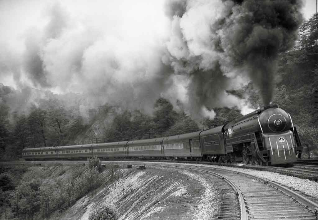A black and white photo of a train turning a corner