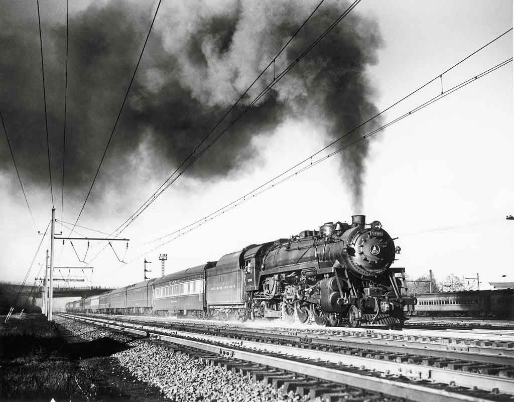 A black and white photo of a train with big black smoke coming out of it