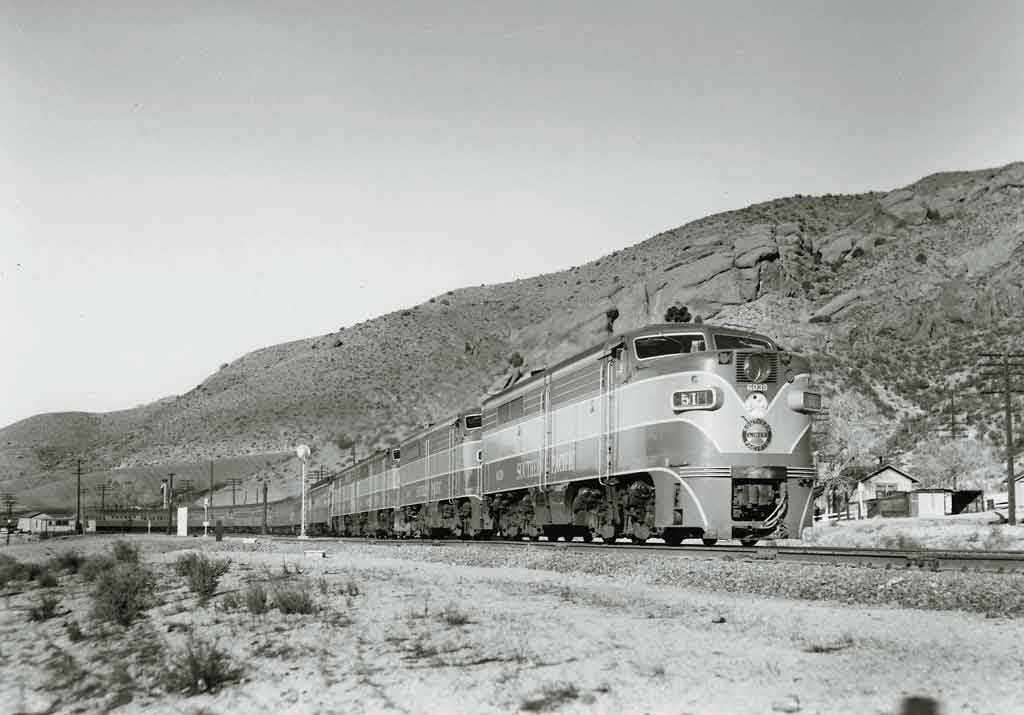 A black and white photo of a locomotive moving pass mountains