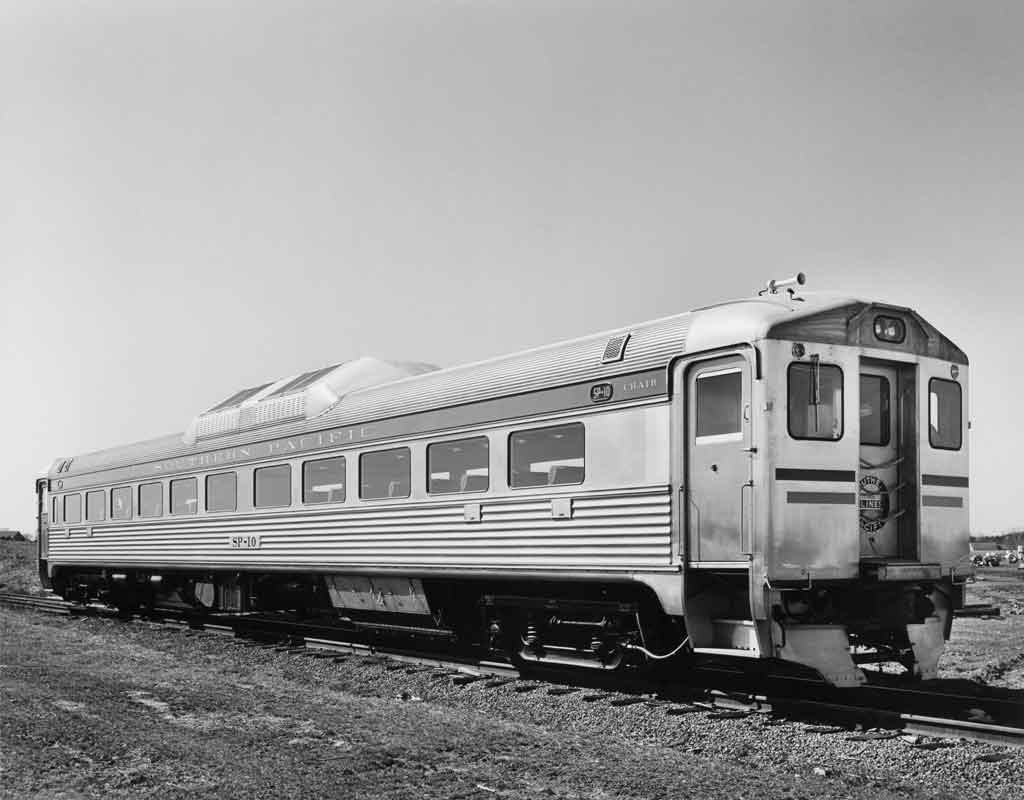 A black and white photo of a diesel car sitting on the tracks