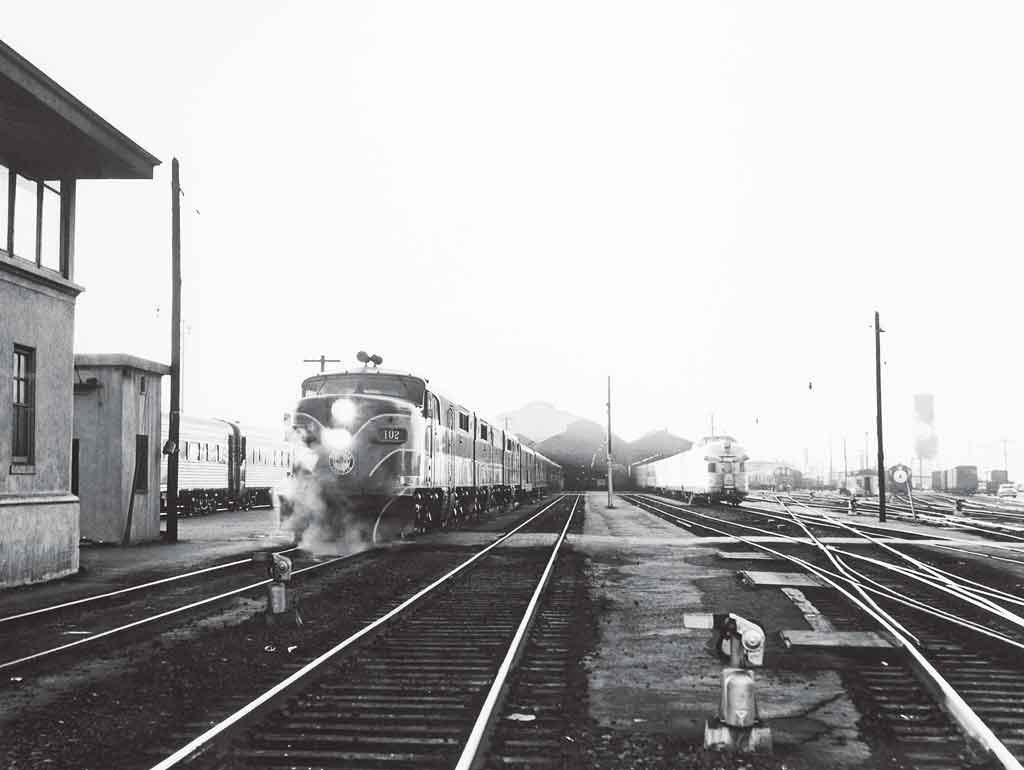A black and white photo of two locomotives leaving a station
