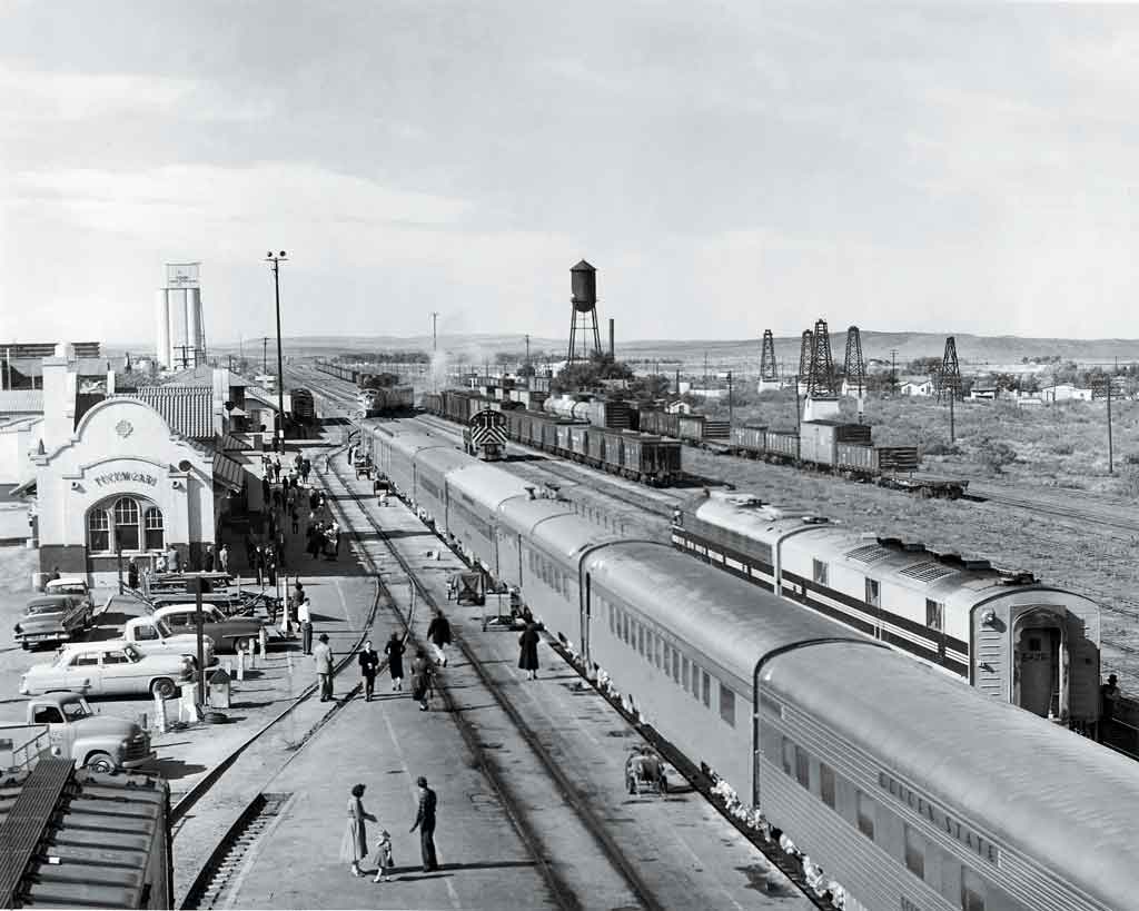 A black and white overhead photo of locomotives and people at a station