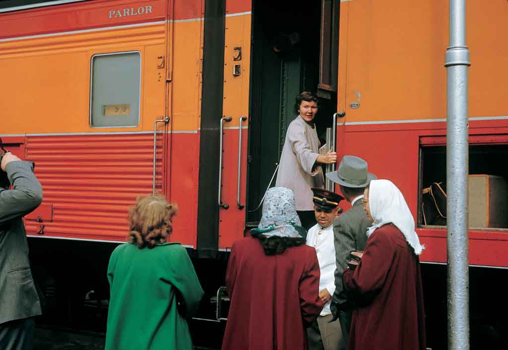 Passengers boarding an orange and red locomotive