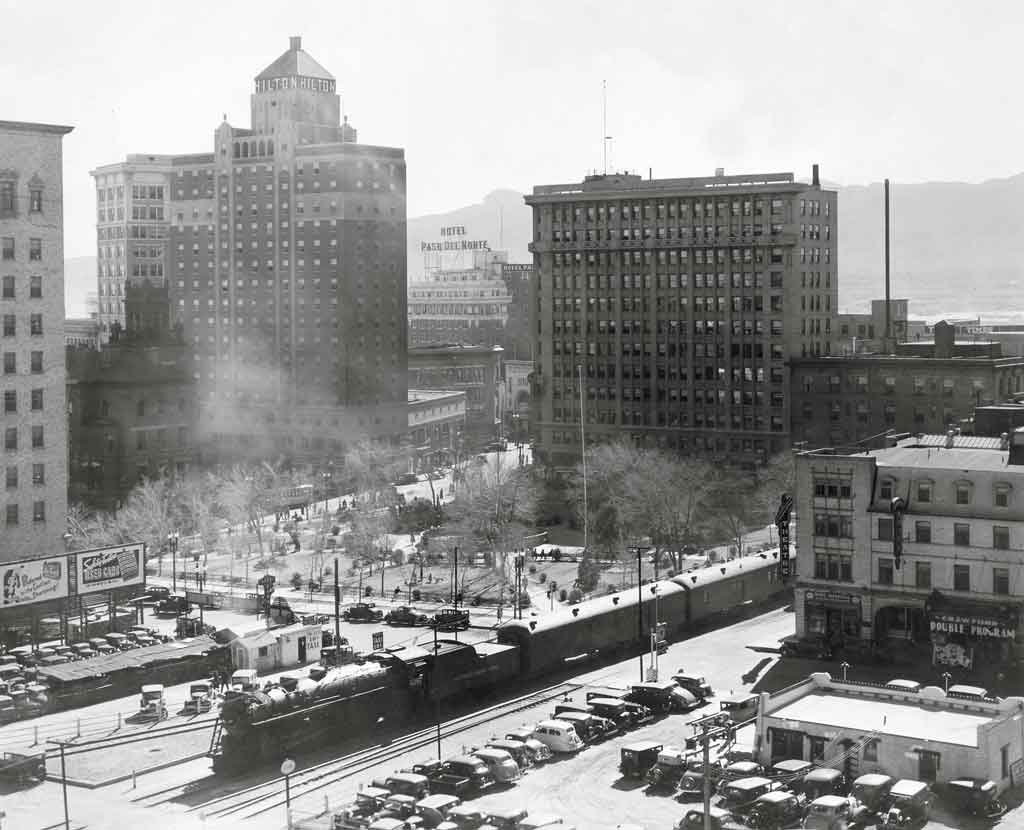 A black and white overhead picture of a locomotive passing through a city in Texas