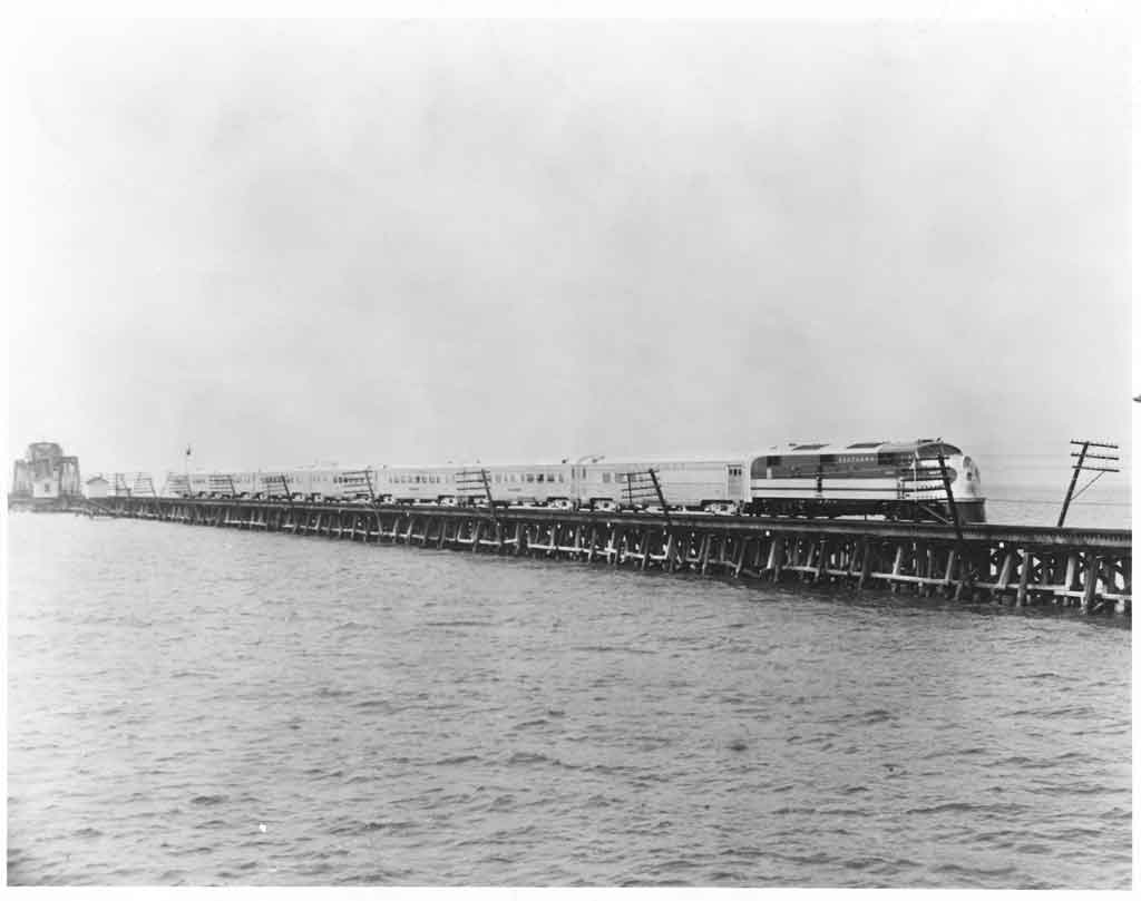 A locomotive crossing a skinny bridge