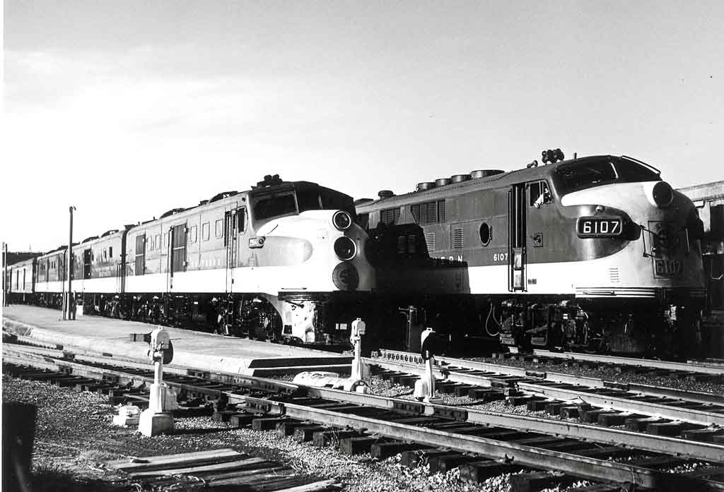 A back and white photo of two locomotives sitting on the tracks