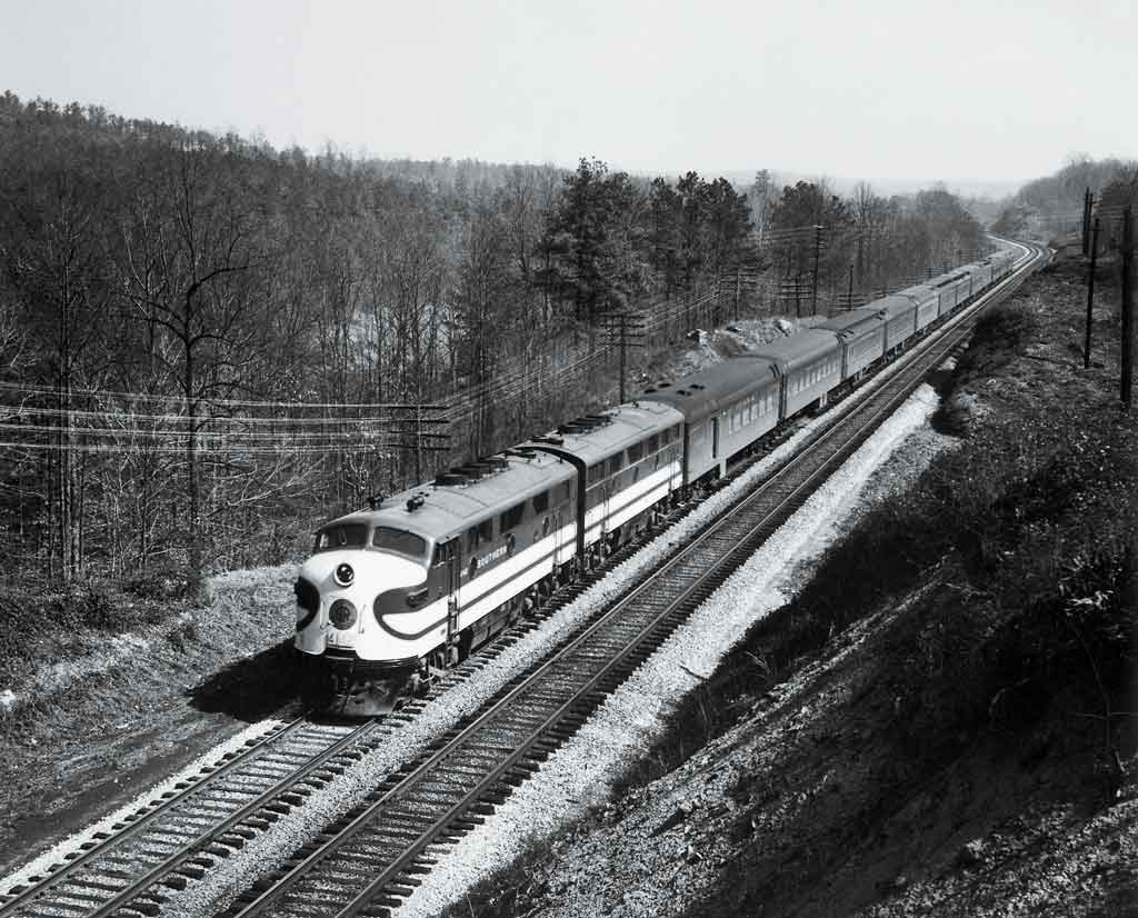 A black and white photo of a locomotive traveling through trees