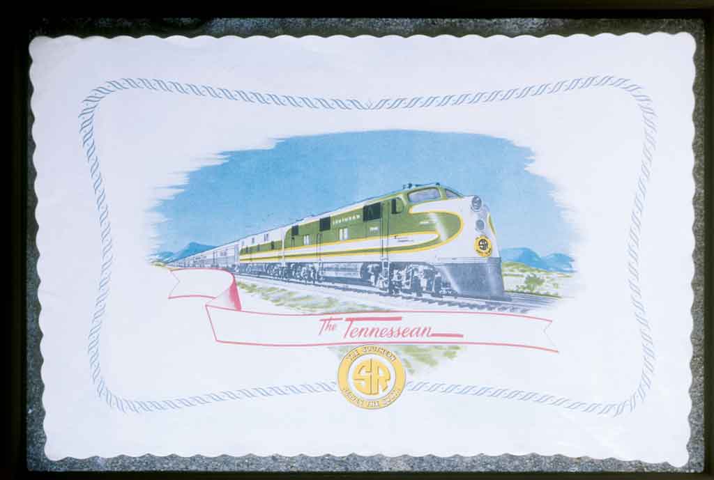 A white placemat with a green and yellow train on it