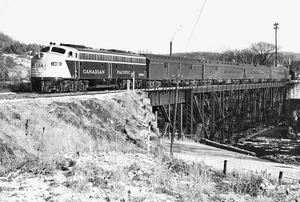 Diesel locomotive on steel bridge with four passenger cars