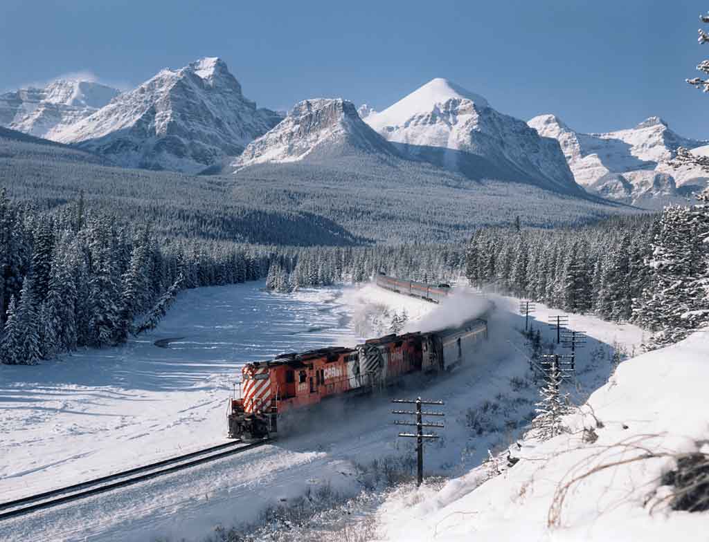 Diesel locomotives in snow amid forests and mountains
